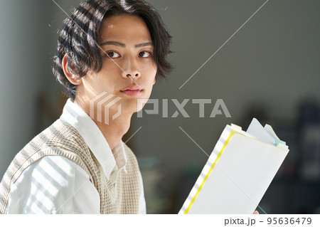 窓辺で読書をする若い男性 95636479