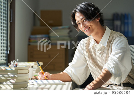 窓辺で勉強をする若い男性 95636504