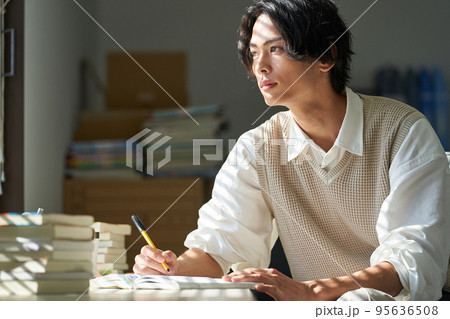 窓辺で勉強をする若い男性 95636508