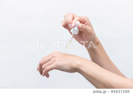 手の甲にスポイトで美容液を 95637200