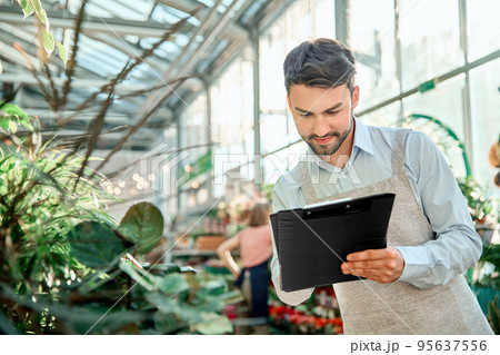 male florist taking notes on the clipboard. male florist taking notes on the clipboard. 95637556