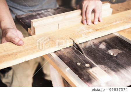 Woodworking operators are using plank cutting machines to assemble and build wooden tables for customers 95637574