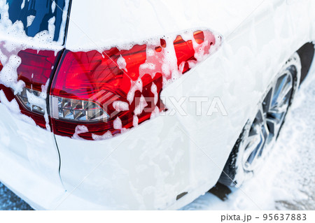 Hand washing with high pressure water in a car wash outside. The car is full of foam. The concept of hand washing, self-service. 95637883