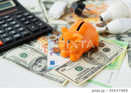 Piggy piggy bank of orange color soit on curry. Calculator, euro and dollar banknotes, coins. Tax time, bill payment, calculator for counting. 95637889