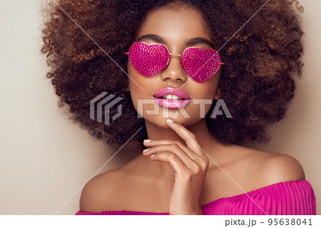 Beautiful portrait of an African girl in sunglasses in the shape of hearts Beautiful portrait of an African girl in sunglasses in the shape of hearts 95638041