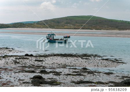 A small fishing boat moored near the shore at low tide. Seaside landscape. Sea. 95638209