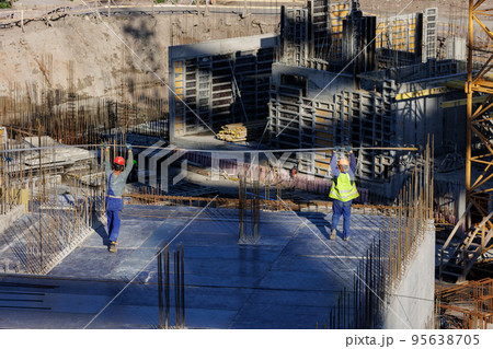 construction of a residential building or a shopping center. engineers and builders in helmets make a monolithic slab of rebar construction of a residential building or a shopping center. engineers and builders in helmets make a monolithic slab of rebar 95638705