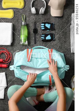 Woman with bag and sports items on grey carpet, top view 95640254