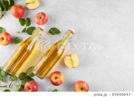 Apple cider vinegar in a two glass bottles and fresh apples with leaves on light background, top view, copy space Apple cider vinegar in a two glass bottles and fresh apples with leaves on light background, top view, copy space 95640647
