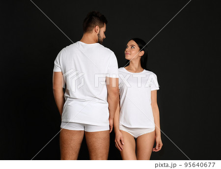 Young couple in white t-shirts and underwear on black background Young couple in white t-shirts and underwear on black background 95640677