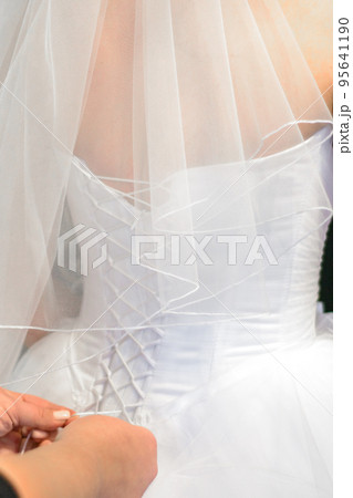 Corset wedding dress being tied by mother's hands 95641190