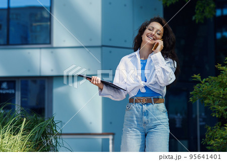 Successful beautiful business woman in suit with document walking to the meeting near modern office building. Successful beautiful business woman in suit with document walking to the meeting near modern office building. 95641401