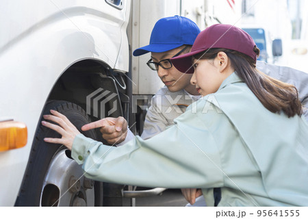 トラックのタイヤを点検する男女のドライバー トラックのタイヤを点検する男女のドライバー 95641555