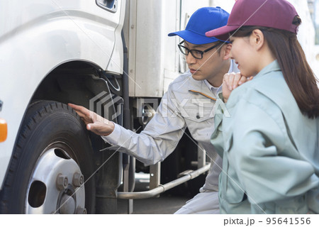 トラックのタイヤを点検する男女のドライバー トラックのタイヤを点検する男女のドライバー 95641556