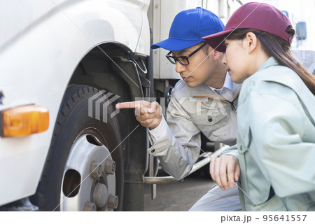 トラックのタイヤを点検する男女のドライバー 95641557