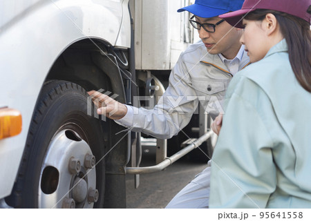 トラックのタイヤを点検する男女のドライバー トラックのタイヤを点検する男女のドライバー 95641558