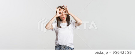 Silly cute brunette girl making hand glasses and showing funny faces Silly cute brunette girl making hand glasses and showing funny faces 95642559
