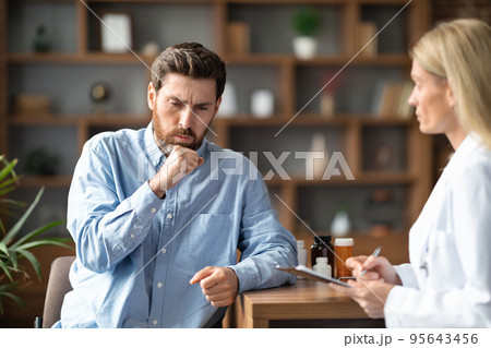 Sick Young Man Coughing During Meeting With Female Doctor In Clinic 95643456