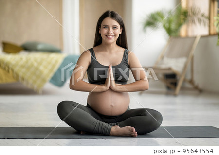 Portrait of happy young pregnant woman practicing yoga at home Portrait of happy young pregnant woman practicing yoga at home 95643554