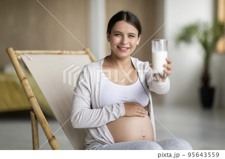 Pregnancy Health. Smiling Expectant Woman Giving Glass With Milk At Camera 95643559