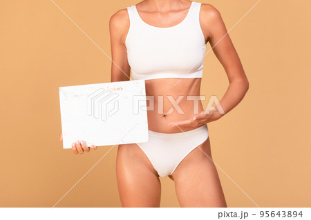 Cropped view of unrecognizable slim woman in top bra and panties holding and pointing at paper calender 95643894
