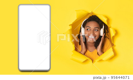 Black Woman Wearing Headphones Near Cellphone Listening Music, Yellow Background Black Woman Wearing Headphones Near Cellphone Listening Music, Yellow Background 95644071