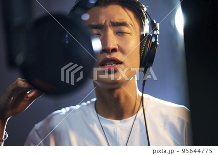 young asian adult man enjoying singing a song in modern recording studio 95644775