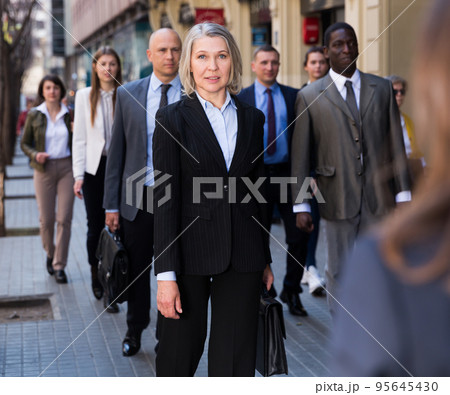 People in formal wear walking down street 95645430