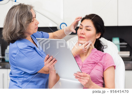 Cosmetologist explaining female client future hardware facial procedure Cosmetologist explaining female client future hardware facial procedure 95645470