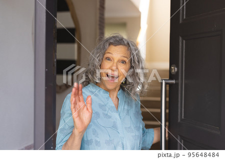 Happy african senior caucasian women opening door and welcoming somebody Happy african senior caucasian women opening door and welcoming somebody 95648484