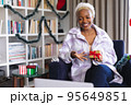 Happy african american woman wearing santa claus hat, using laptop for video call 95649851