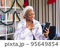 Happy african american woman wearing santa claus hat, using smartphone for video call 95649854