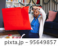 Happy african american woman wearing santa claus hat, packing presents 95649857