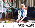 Happy african american woman wearing santa claus hat, packing presents 95649865