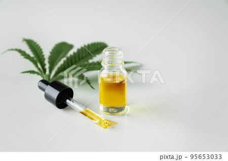 Legalized cannabis sativa hemp leaf and container of CBD oil with dropper lid. Legalized cannabis sativa hemp leaf and container of CBD oil with dropper lid. 95653033