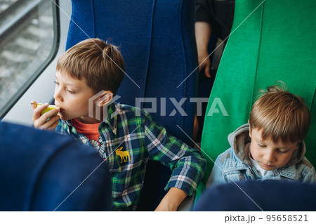 children travelling by train. Boys sitting in train car and looking through window children travelling by train. Boys sitting in train car and looking through window 95658521