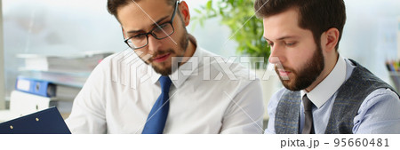 Coworkers men go through financial papers, solve and discuss problems Coworkers men go through financial papers, solve and discuss problems 95660481