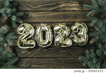 New year 2023 balloon. Gold foil helium balloon number 2023, party decoration on wooden background with fir branches 95661433