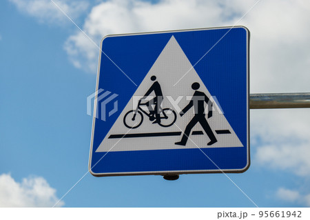 Cyclist and pedestrian route sharing sign. Road sign Pedestrian and bicycle can cross the street here on the background of blue sky  95661942