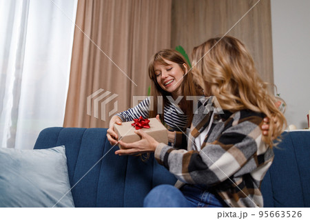 Cute young woman giving her mother gift box at home 95663526