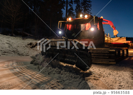 Snowcat ratrack machine making snow at ski resort. Snow grooming at night 95663588