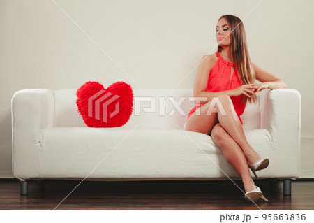 Sad woman with heart shape pillow. Valentines day. 95663836