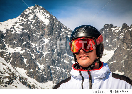 Male skier with ski goggles and helmet and snowy peak at background Male skier with ski goggles and helmet and snowy peak at background 95663973