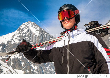 Male skier with ski goggles, helmet and skis posing in front of Lomnicky peak in High Tatras mountains 95663974