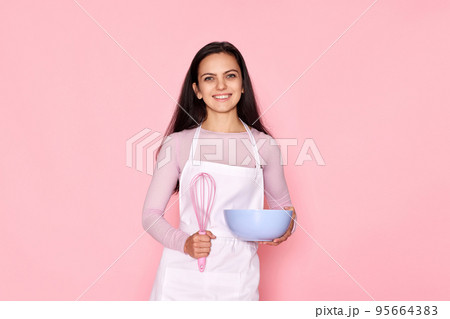 woman holding whisk and bowl with eggs 95664383