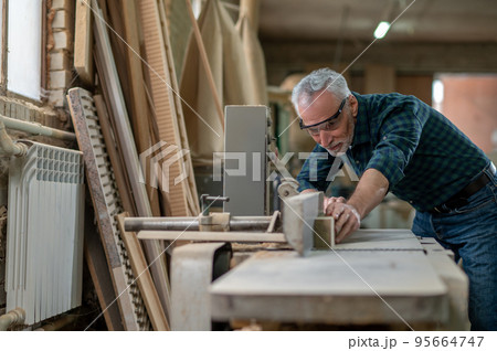 Mature carpenter working in a workshop and looking involved 95664747