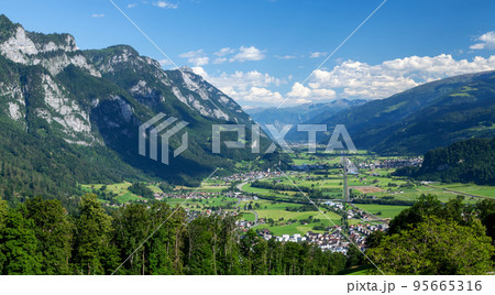 Panoramic view of countryside, green alpine meadows and mountains Panoramic view of countryside, green alpine meadows and mountains 95665316