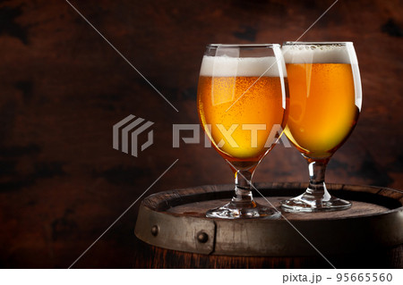 Two beer glasses on wooden barrel 95665560