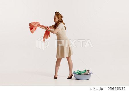 Portrait of young elegant woman washing clothes isolated over white background. Squeezing water 95666332