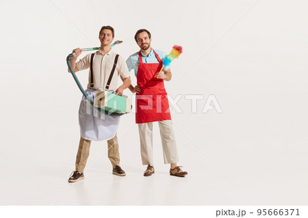 Portrait of two men in aprons with vacuum cleaner and pipidastre isolated over white background. Male cleaning service 95666371